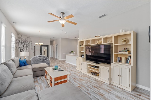 living room featuring a textured ceiling, ceiling fan with notable chandelier, and light wood-type flooring