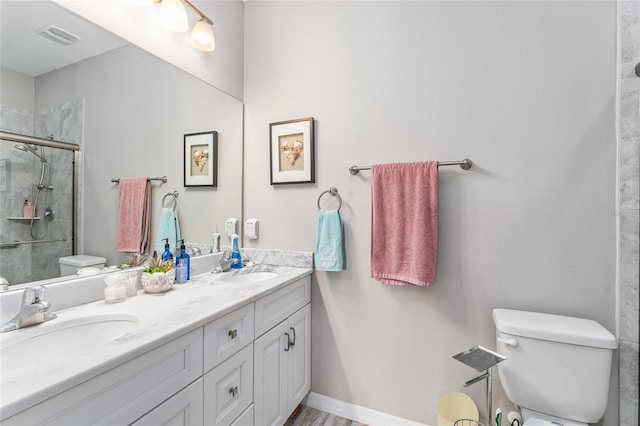 bathroom featuring vanity, toilet, and a shower with door