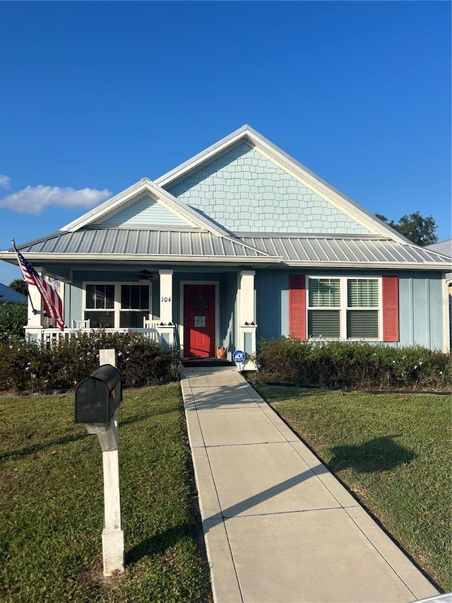 104 Turtle Run, Umatilla, FL 32784 - view of front facade with covered porch, board and batten siding, a front yard, and metal roof