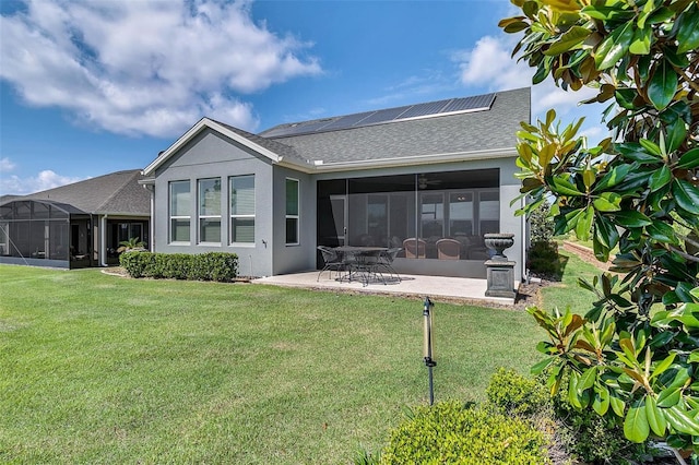 rear view of property featuring solar panels, a sunroom, a yard, and a patio area