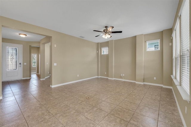 spare room with light tile patterned floors, a wealth of natural light, and ceiling fan