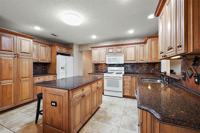 kitchen featuring white appliances, a textured ceiling, sink, and a kitchen island