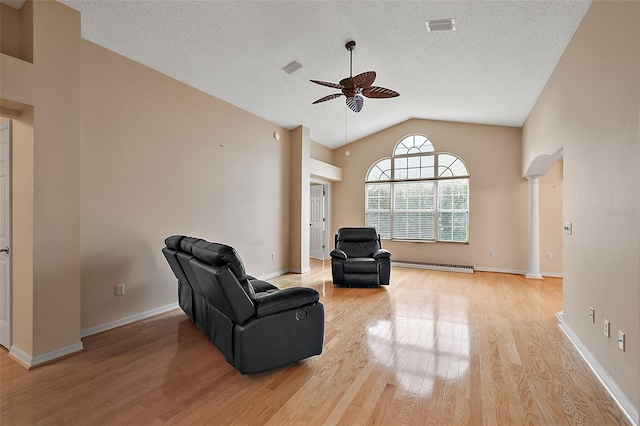 sitting room featuring a baseboard heating unit, ceiling fan, light wood-type flooring, vaulted ceiling, and ornate columns