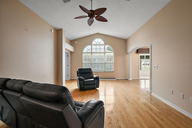 living room with lofted ceiling, ornate columns, baseboard heating, light wood-type flooring, and ceiling fan