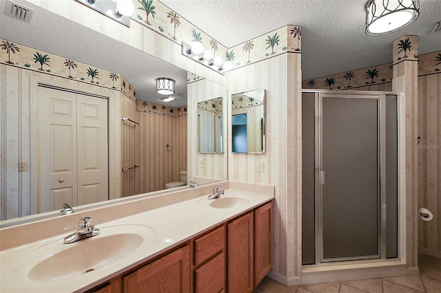 bathroom with a textured ceiling, a shower with shower door, toilet, tile patterned floors, and vanity