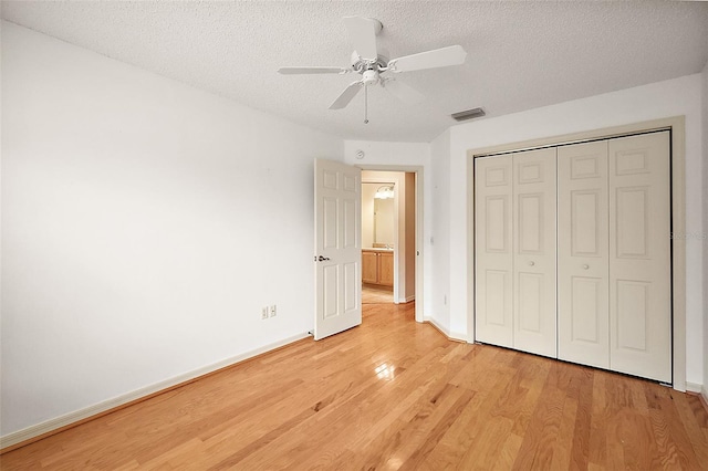 unfurnished bedroom featuring light hardwood / wood-style flooring, a textured ceiling, a closet, and ceiling fan