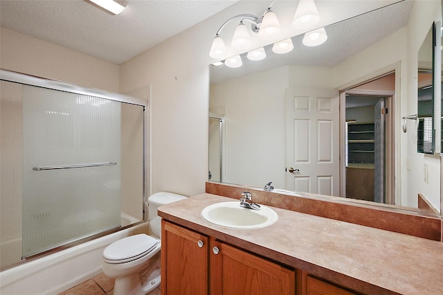 full bathroom featuring combined bath / shower with glass door, a textured ceiling, toilet, vanity, and tile patterned flooring