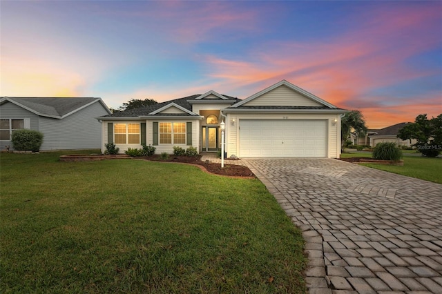 ranch-style home featuring a garage, decorative driveway, and a front yard