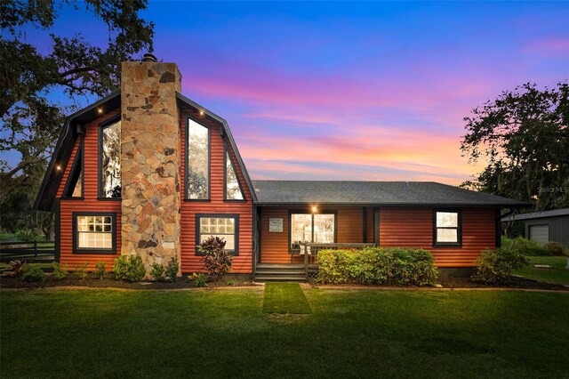 back house at dusk featuring a yard