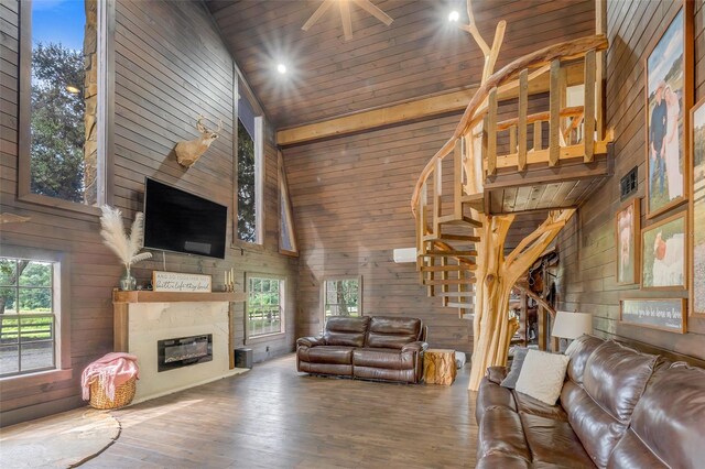 living room featuring ceiling fan, wood ceiling, wood walls, wood-type flooring, and high vaulted ceiling