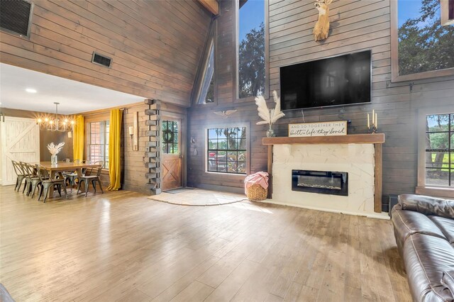 living room with wooden walls, a fireplace, plenty of natural light, and high vaulted ceiling