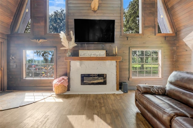 living room featuring wood ceiling, wood walls, wood-type flooring, a premium fireplace, and high vaulted ceiling