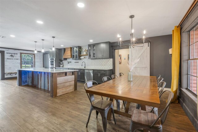 dining space with sink, dark wood-type flooring, a chandelier, and a barn door