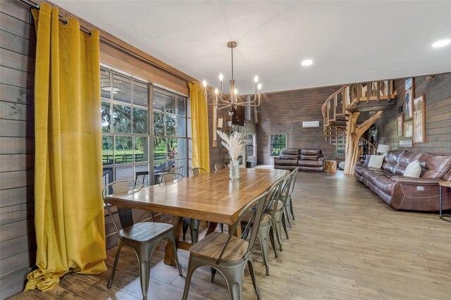 dining room featuring an inviting chandelier, wood walls, and light hardwood / wood-style floors