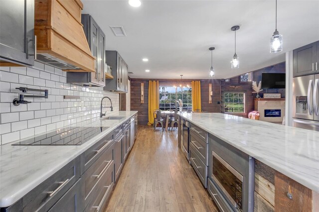 kitchen with wooden walls, hardwood / wood-style flooring, decorative light fixtures, and sink