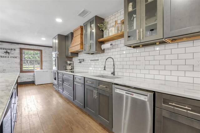 kitchen with light stone countertops, decorative backsplash, sink, and stainless steel appliances