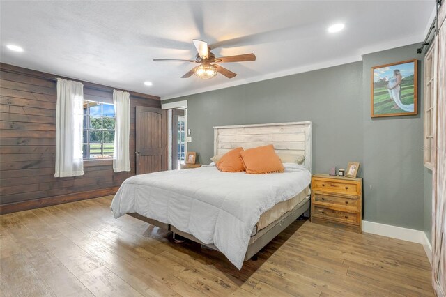 bedroom featuring wood-type flooring, wood walls, and ceiling fan