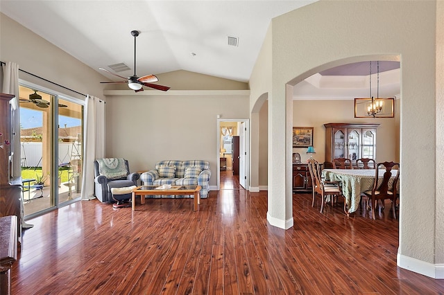 living area featuring ceiling fan with notable chandelier, vaulted ceiling, and dark hardwood / wood-style floors