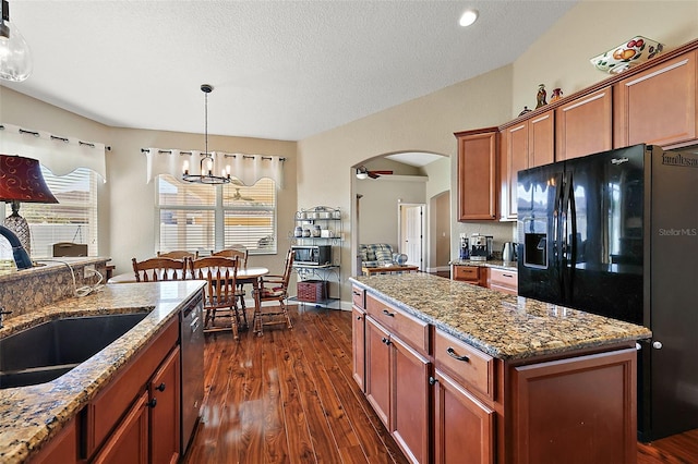 kitchen with a kitchen island, a textured ceiling, dark hardwood / wood-style floors, black fridge, and sink