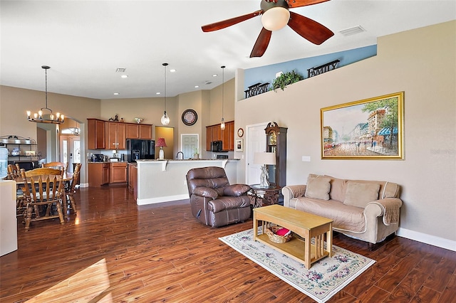 living room featuring ceiling fan with notable chandelier, high vaulted ceiling, and dark wood-type flooring