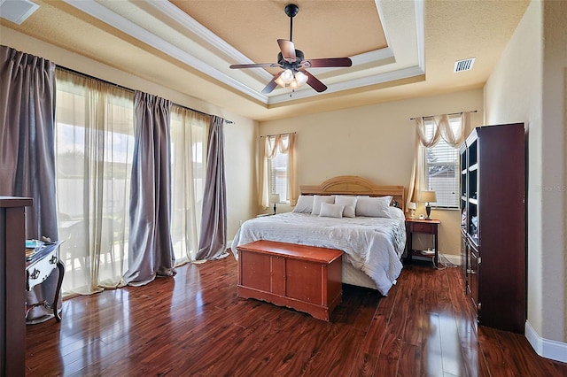 bedroom with a tray ceiling, ceiling fan, dark hardwood / wood-style floors, and a textured ceiling