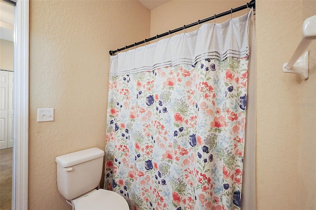 bathroom with toilet and a shower with curtain