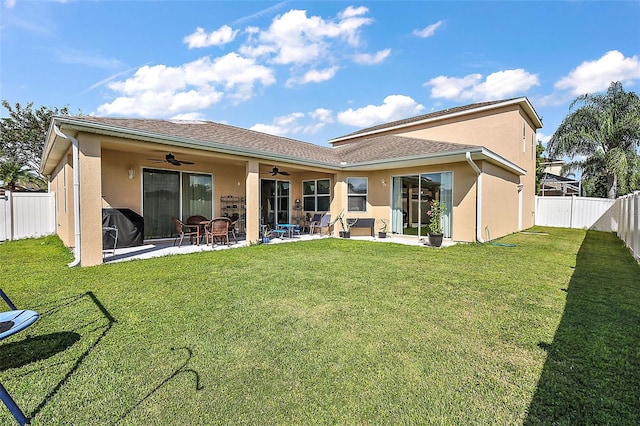 rear view of house with ceiling fan, a yard, and a patio area