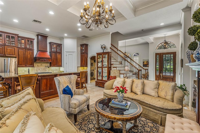 tiled living room with a chandelier, beamed ceiling, stacked washer / drying machine, coffered ceiling, and ornamental molding