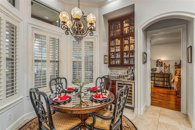 dining room featuring ornamental molding, an inviting chandelier, light hardwood / wood-style flooring, and wine cooler