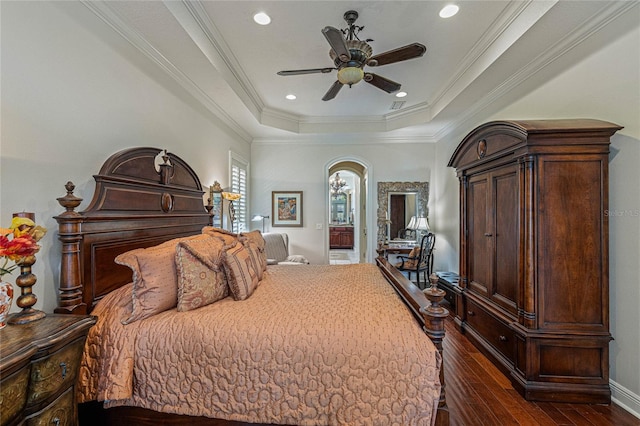 bedroom with ceiling fan, a tray ceiling, dark hardwood / wood-style floors, and crown molding