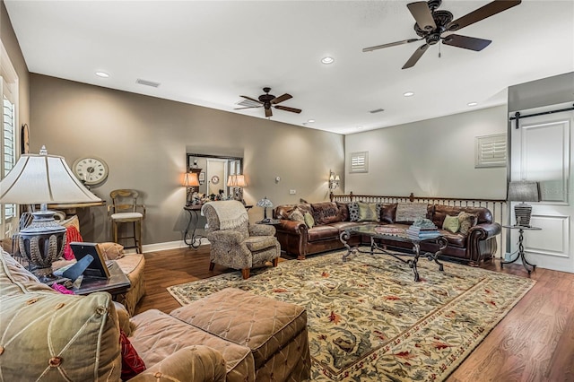 living room with a barn door, ceiling fan, and hardwood / wood-style flooring