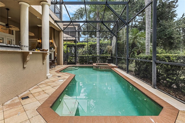 view of pool with glass enclosure, a patio, an in ground hot tub, exterior bar, and ceiling fan