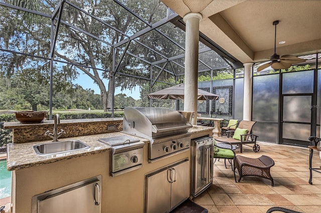 view of patio / terrace featuring glass enclosure, area for grilling, sink, and ceiling fan