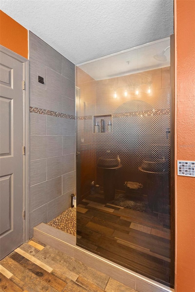 bathroom featuring a tile shower, wood-type flooring, and a textured ceiling