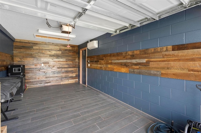 garage featuring a garage door opener, wood walls, and a wall mounted air conditioner