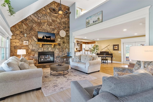 living room with light hardwood / wood-style floors, a stone fireplace, and plenty of natural light