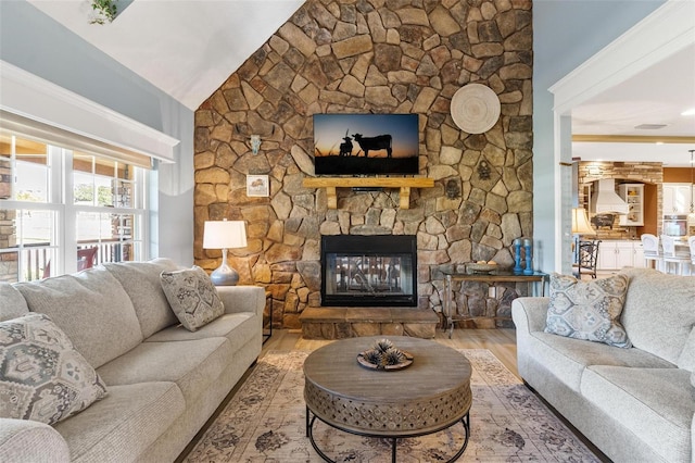 living room with hardwood / wood-style flooring, vaulted ceiling, and a stone fireplace