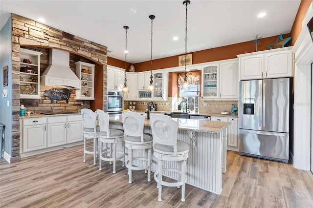 kitchen featuring premium range hood, white cabinets, a kitchen island with sink, and stainless steel appliances