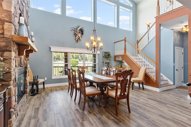 dining space with a towering ceiling, a chandelier, plenty of natural light, and hardwood / wood-style floors