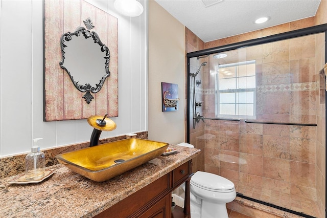 bathroom featuring vanity, toilet, walk in shower, and a textured ceiling