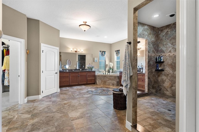 bathroom featuring vanity, a tile shower, and a textured ceiling