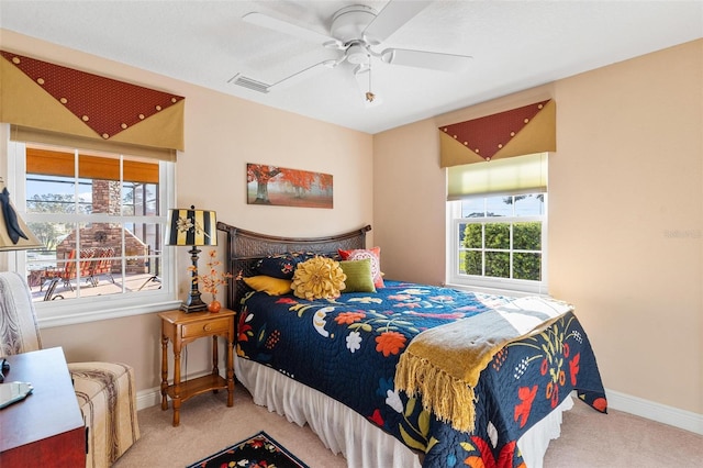 bedroom with ceiling fan, light carpet, and multiple windows