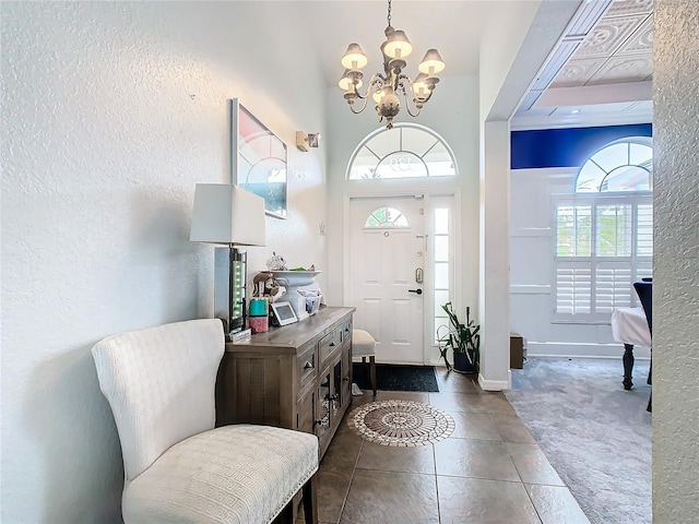 entrance foyer with a notable chandelier, dark tile patterned flooring, and a high ceiling