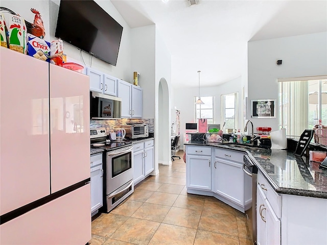 kitchen with hanging light fixtures, sink, white cabinetry, appliances with stainless steel finishes, and dark stone counters