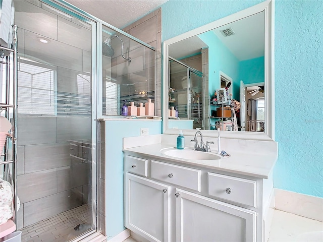 bathroom with a textured ceiling, vanity, and an enclosed shower