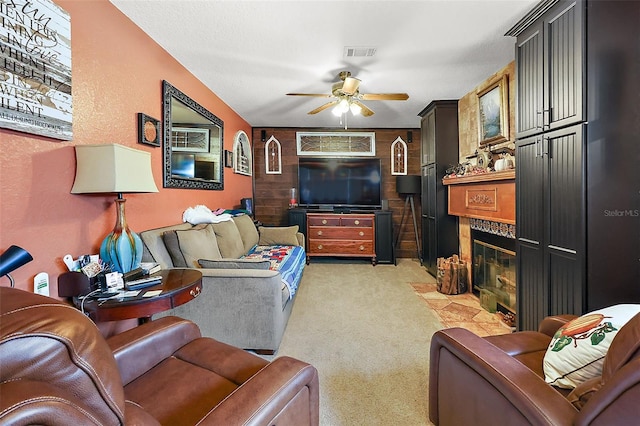 carpeted living room featuring a fireplace and ceiling fan