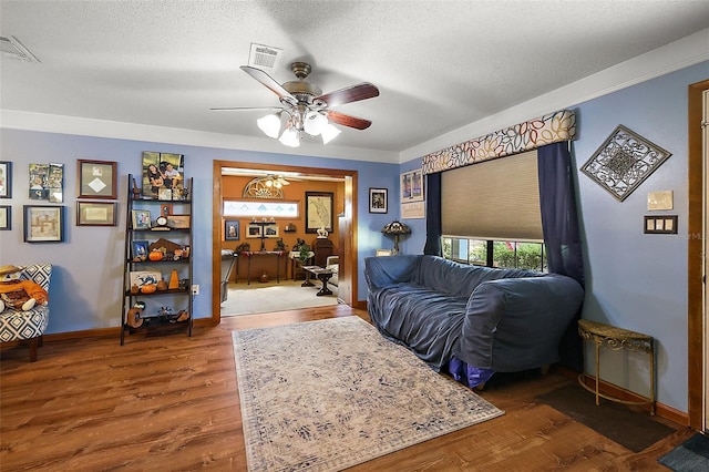 living room with a textured ceiling, crown molding, ceiling fan, and hardwood / wood-style flooring