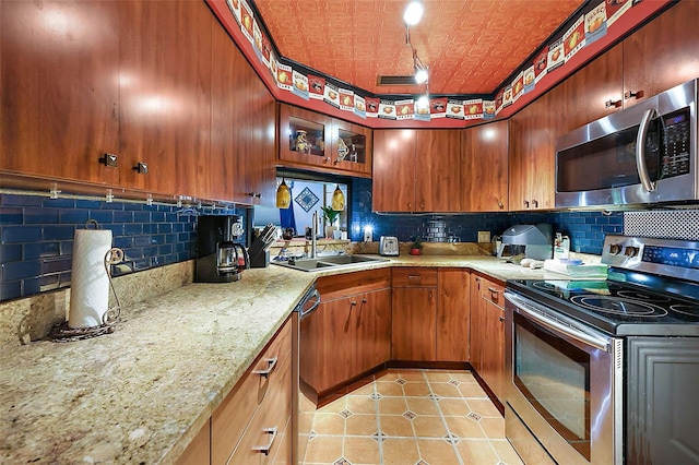 kitchen featuring light stone countertops, stainless steel appliances, decorative backsplash, and sink