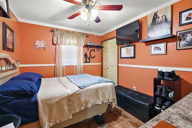 bedroom with a closet, ceiling fan, wood-type flooring, and crown molding