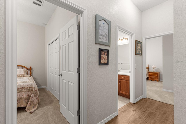 hallway with light carpet and a textured ceiling